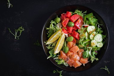 Ketogenik, keto veya tuzlu somon balığı, limon, salatalık, zeytin, domates, yeşil salata ve ballı hardal soslu paleo diyet kasesi. Sağlıklı beslenme eğilimi. Üst görünüm