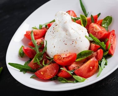 Domatesli salata ve fesleğen ve zeytinyağlı burrata peyniri. İtalyan yemeği..
