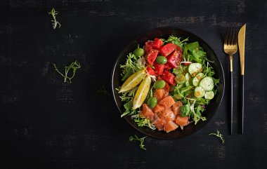 Ketogenik, keto veya tuzlu somon balığı, limon, salatalık, zeytin, domates, yeşil salata ve ballı hardal soslu paleo diyet kasesi. Sağlıklı beslenme eğilimi. Üst görünüm