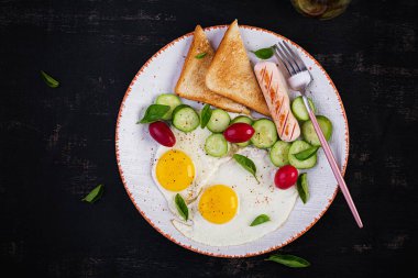 İngiliz kahvaltısı, sahanda yumurta, sosis, salatalık ve tost. Amerikan yemeği. Üst manzara, düz uzanma