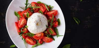 Domatesli salata ve fesleğen ve zeytinyağlı burrata peyniri. İtalyan yemeği. Üst manzara, düz uzanma