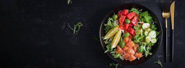 Ketogenik, keto veya tuzlu somon balığı, limon, salatalık, zeytin, domates, yeşil salata ve ballı hardal soslu paleo diyet kasesi. Sağlıklı beslenme eğilimi. Üst görünüm, afiş
