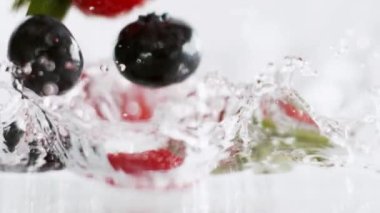 Yavaş hareket et, MACRO, DOF: sarı ayçiçeği yağı damlası su dolu bir lavaboya düşer. Parlak bir yağ damlasının yavaş çekim görüntüsü soğuk suyun içine düştükten sonra dalgalanma yaratır..