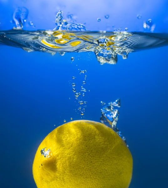 Limón amarillo en agua salpicada — Foto de Stock