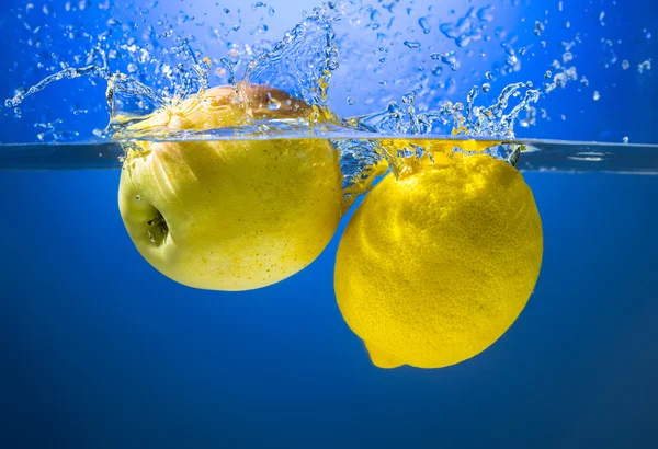 Yellow lemon and apple in water splash — Stock Photo, Image