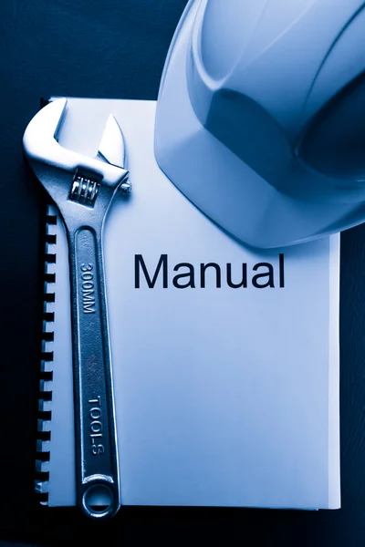 Manual with helmet and spanner — Stock Photo, Image