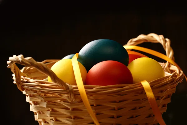 Easter eggs with yellow ribbon in basket — Stock Photo, Image