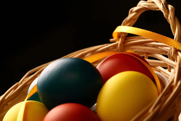 Easter eggs with yellow ribbon in basket — Stock Photo, Image