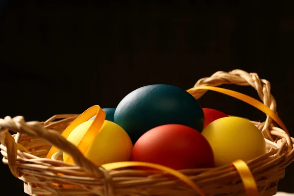 Easter eggs with yellow ribbon in basket — Stock Photo, Image