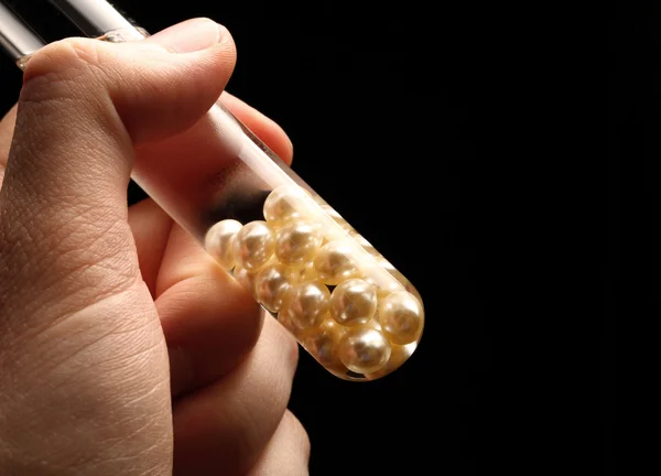 Hand holding test tube with white pearls — Stock Photo, Image