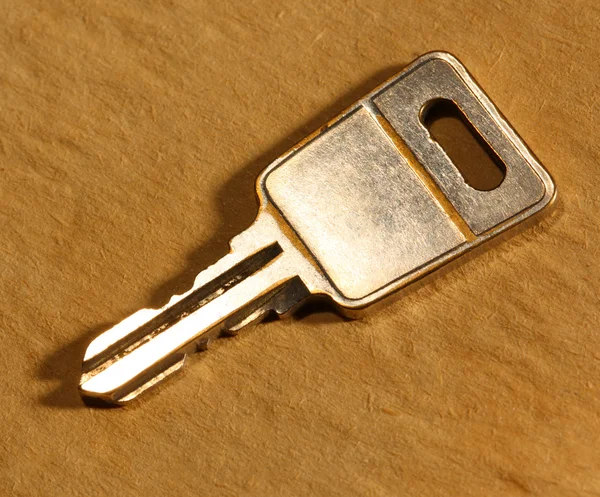 Metal key on paper background — Stock Photo, Image