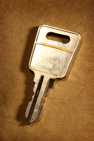 Metalen sleutel op papier achtergrond — Stockfoto