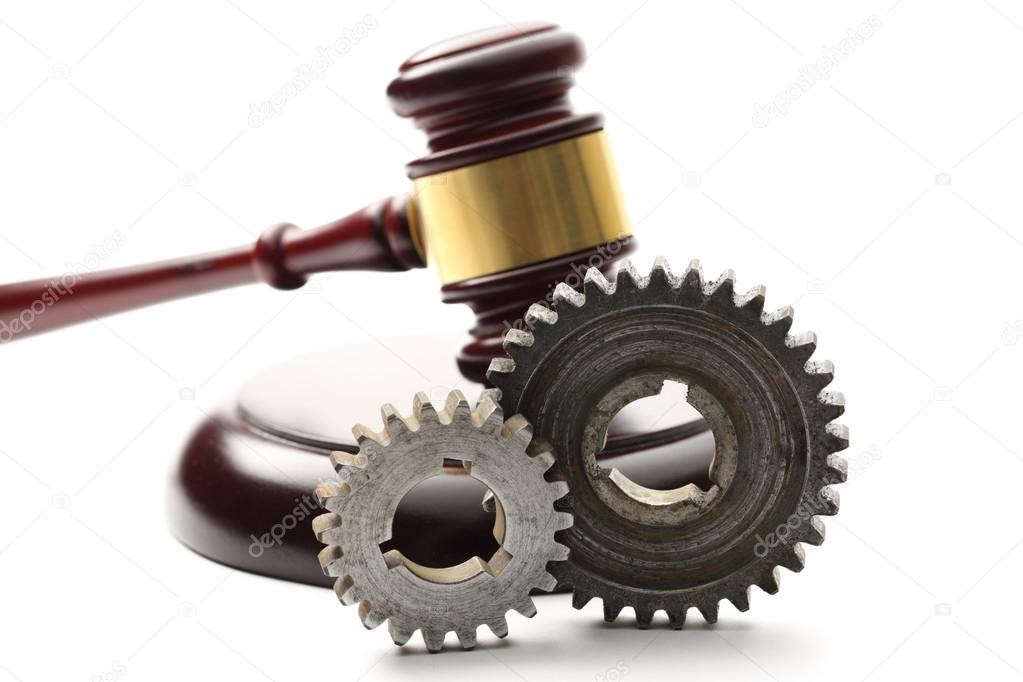 Steel cogwheels on judge's wooden gavel background