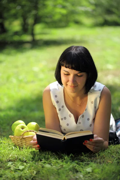 Young woman reading book on grass — Stock Photo, Image