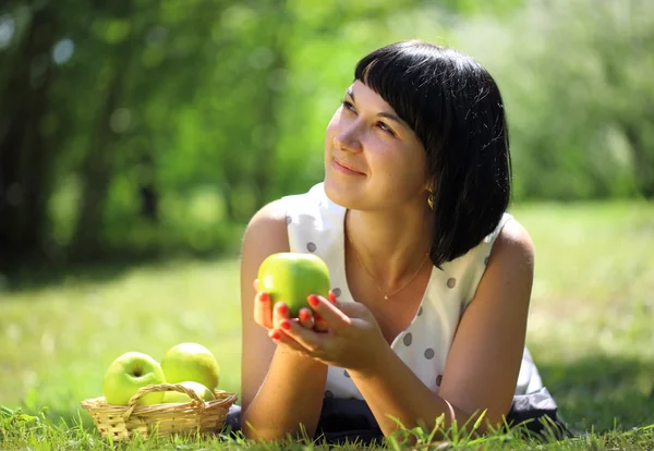 Young woman with apples lying on grass — Stock Photo, Image