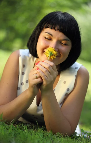 Young woman lying on grass with dandelion — Stock Photo, Image