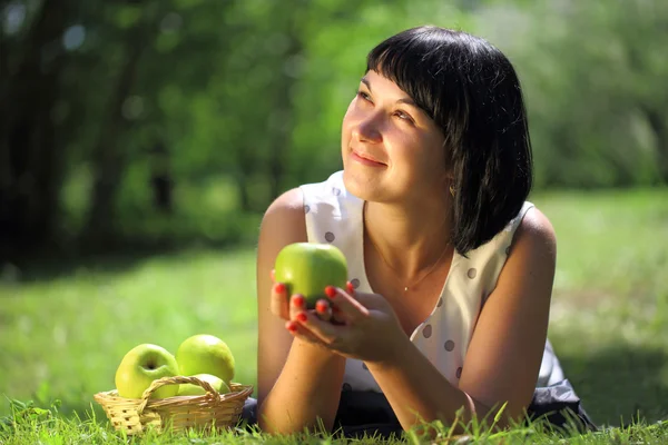 Giovane donna con mele sdraiata sull'erba — Foto Stock