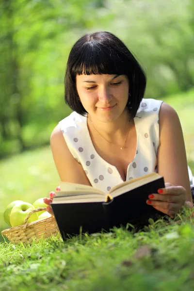 Young woman reading book on grass — Stock Photo, Image