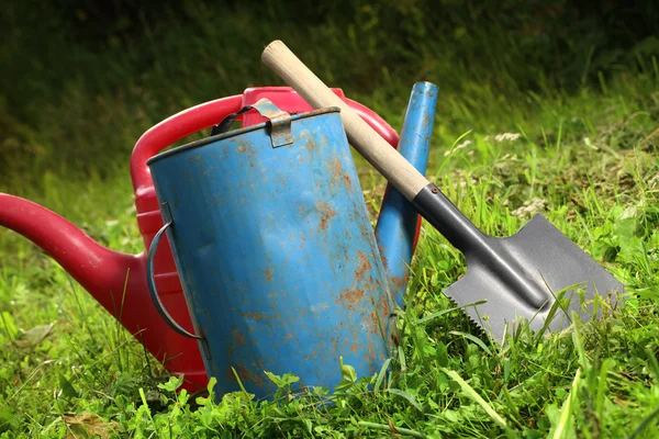 Oude gieters en shovel op gras — Stockfoto