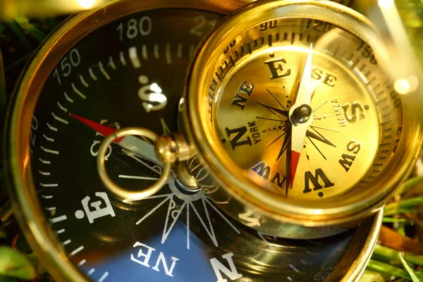 Dva zlaté kompasy na zelené trávě — Stock fotografie