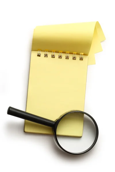 Yellow notepad and magnifying glass — Stock Photo, Image