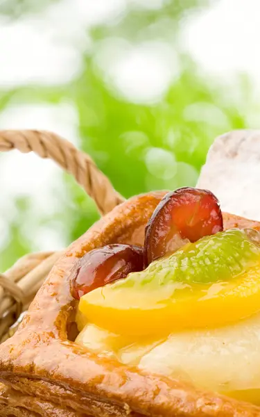 Basket of buns on green leaves background — Stok fotoğraf