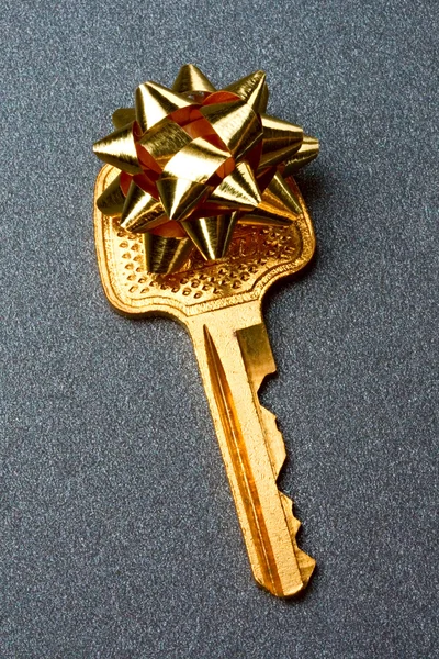 Ключ с бантом на сером фоне — стоковое фото