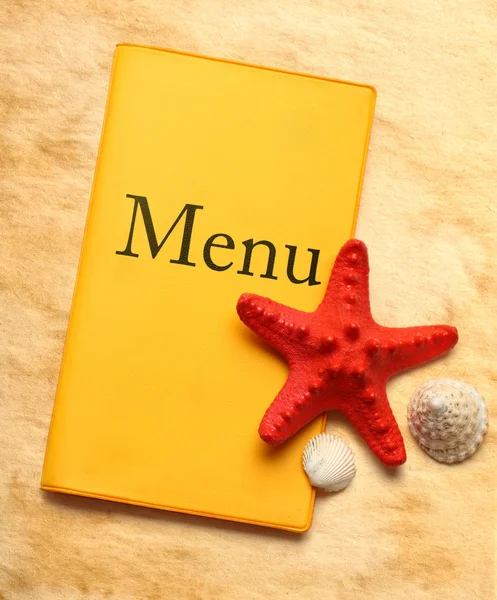 Żółty menu książki, seastar i muszle — Zdjęcie stockowe