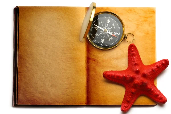Kompas a červené seastar na otevřené knize — Stock fotografie