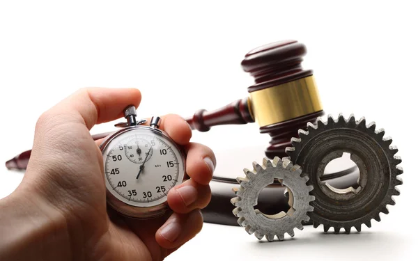 Steel cogwheels, wooden gavel and stopwatch in hand — Stock Photo, Image