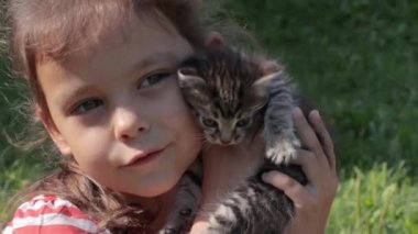 Elinde kedi yavrusu olan küçük kız.