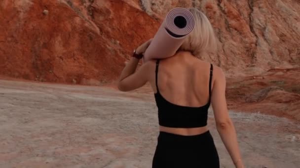 Stoprty woman walking with yoga mat on desert location — Wideo stockowe