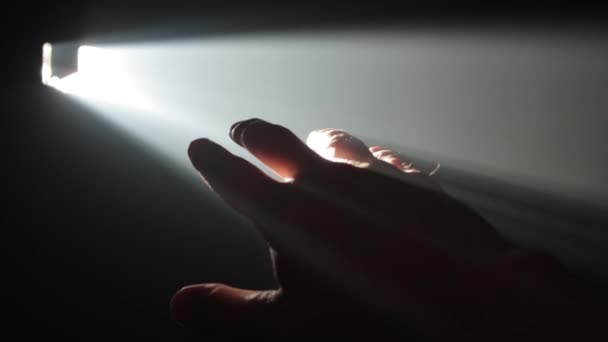 De man die zijn hand tegen een lichtstraal houdt — Stockvideo