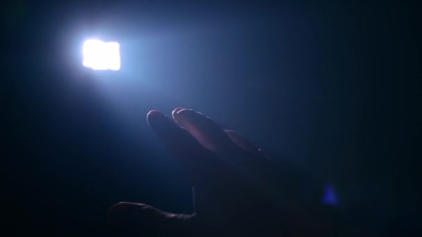 Ο άνθρωπος κρατά το χέρι του ενάντια στην ακτίνα του φωτός — Αρχείο Βίντεο