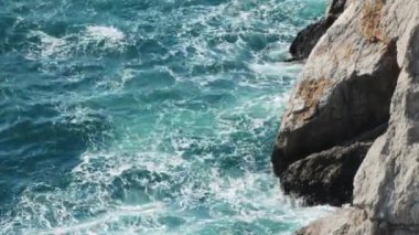 Deniz suyu kayalık kıyıları yıkıyor.
