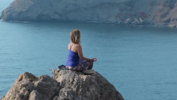 Une femme méditant sur un rocher — Video