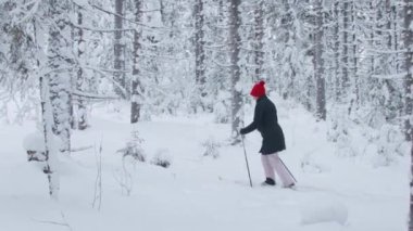 Ormanda derin karlar içinde yürüyen bir kadın.