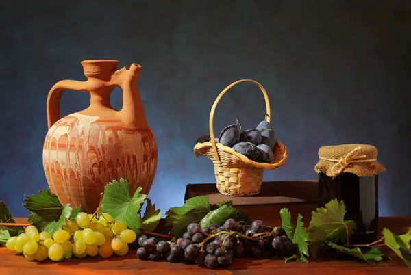 Keramikkrug und Pflaumen im Weidenkorb — Stockfoto