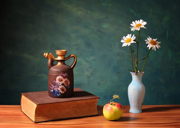 Bloemen in een vaas, boeken en apple — Stockfoto