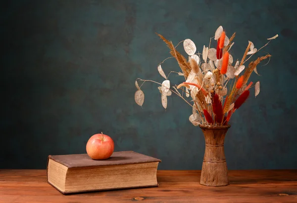 Gedroogde bloemen in een vaas en boeken — Stockfoto