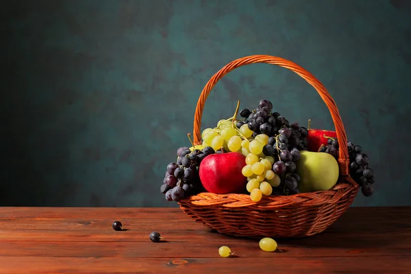 葡萄和柳条编织的篮子里的苹果 — 图库照片