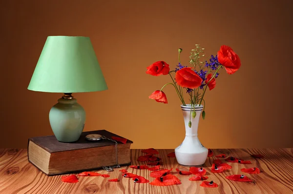 Röd vallmo i en vas och tabell lampa — Stockfoto