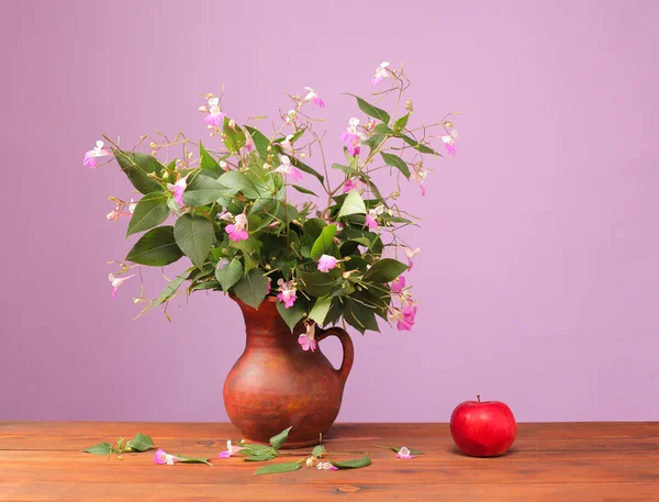 Flowers in a vase and red apple — Stock Photo, Image
