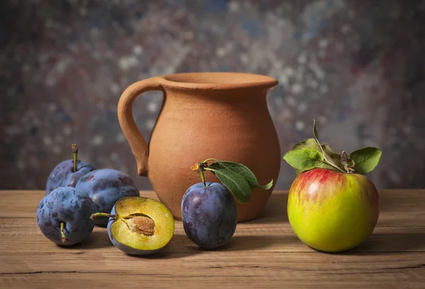 Ciruelas frescas, manzanas y una jarra de cerámica —  Fotos de Stock