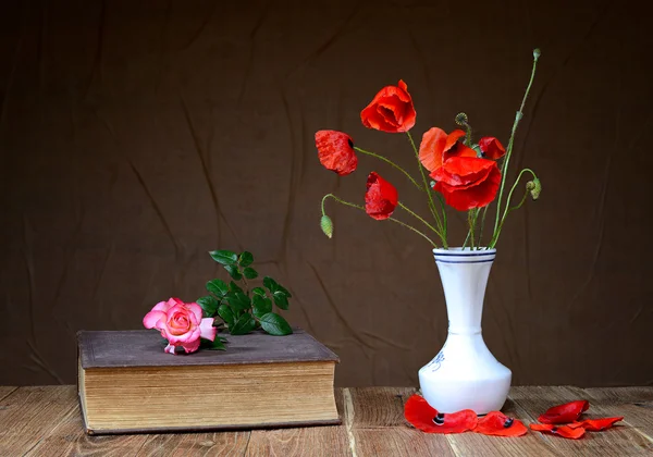 Coquelicot rouge dans un vase et roses sur un livre — Photo