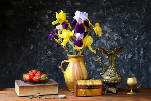 Irises in a ceramic vase and fresh strawberries — Stock Photo, Image