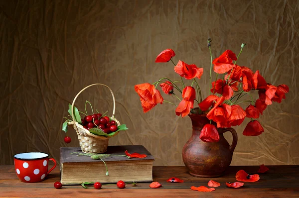 Red poppies in a ceramic vase, books,cherries and metal pots — Stock Photo, Image