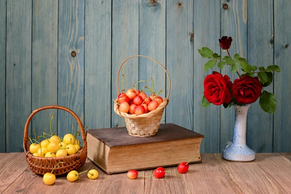 Sötkörsbär, böcker och blommor i en vas — Stockfoto