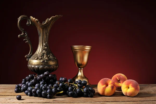 Metal carafe, grapes and peaches — Stock Photo, Image