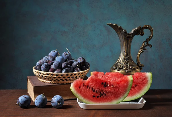 Watermeloen segmenten en pruimen in wickerbasket — Stockfoto